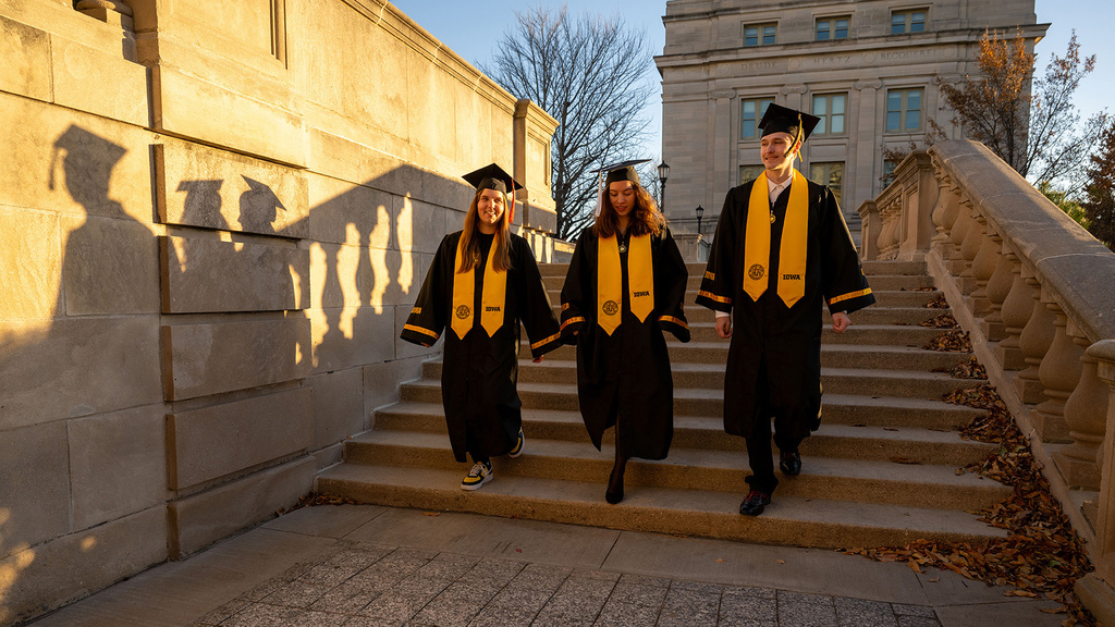 three University of Iowa grads walking down steps on the pentacrest