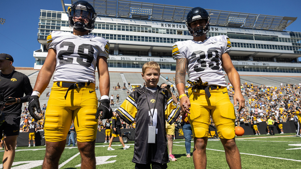 A young boy standing between two football players