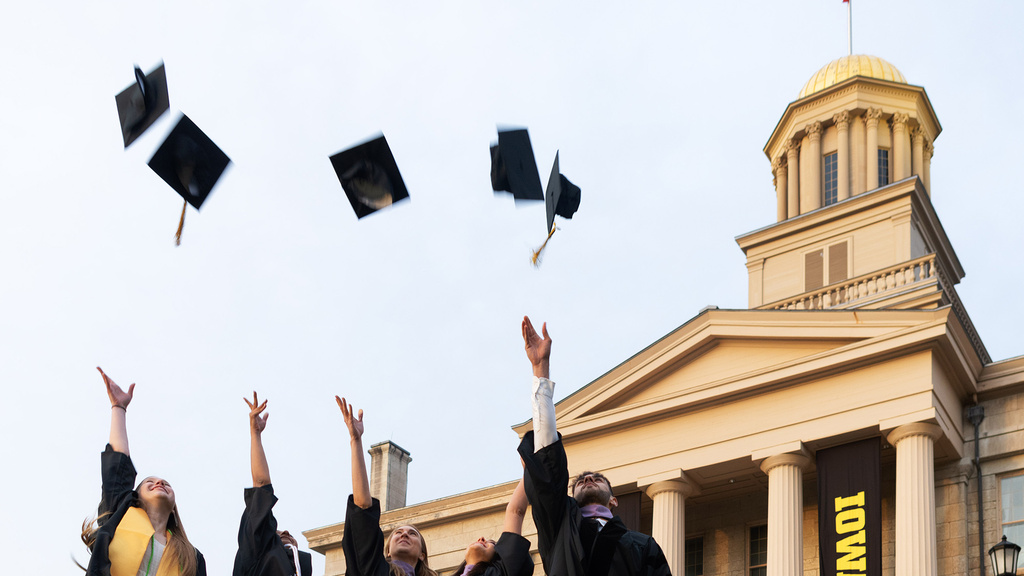grads standing near old capitol, throwing caps in the air
