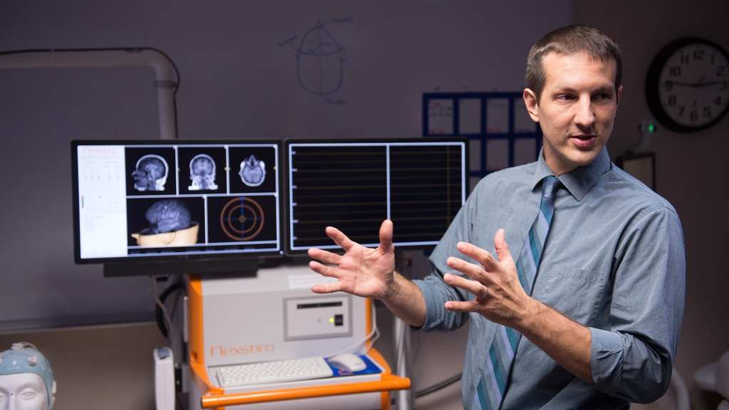 A man explaining some images on a screen behind him