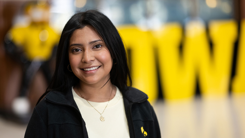 University of Iowa grad Brenda Ramirez with a Herky statue and an Iowa sign out of focus in the background