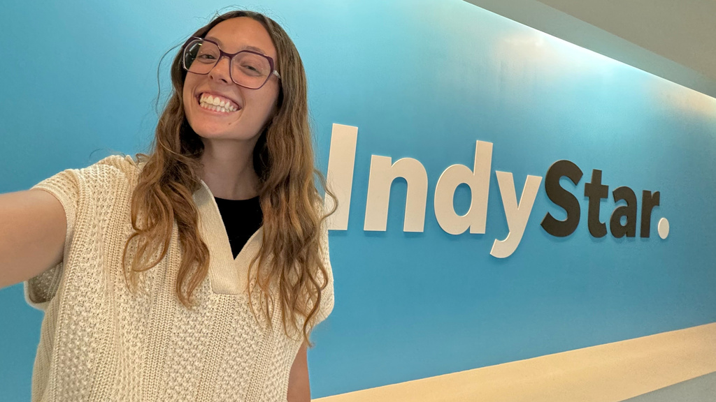 University of Iowa grad Grace Smith taking a selfie in front of the Indy Star logo on a wall