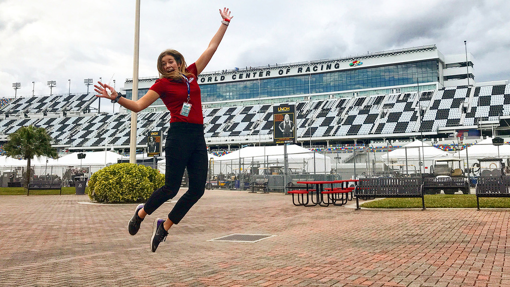 a woman leaping in the air outside of a race track