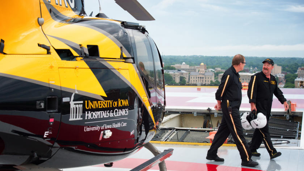 two men walking away from a helicopter that is on a helipad