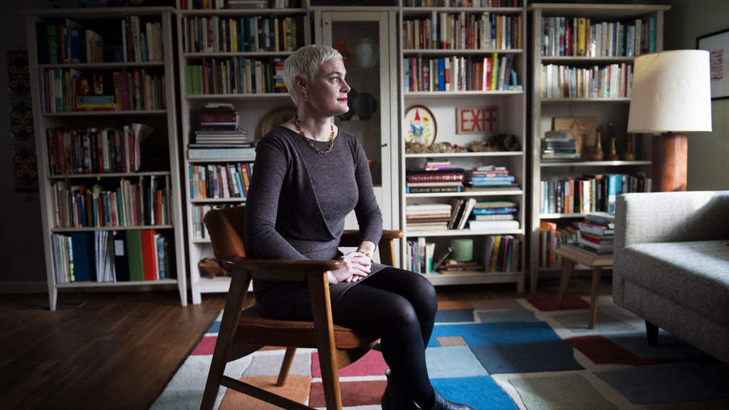 A woman sitting in a room with a wall lined with books