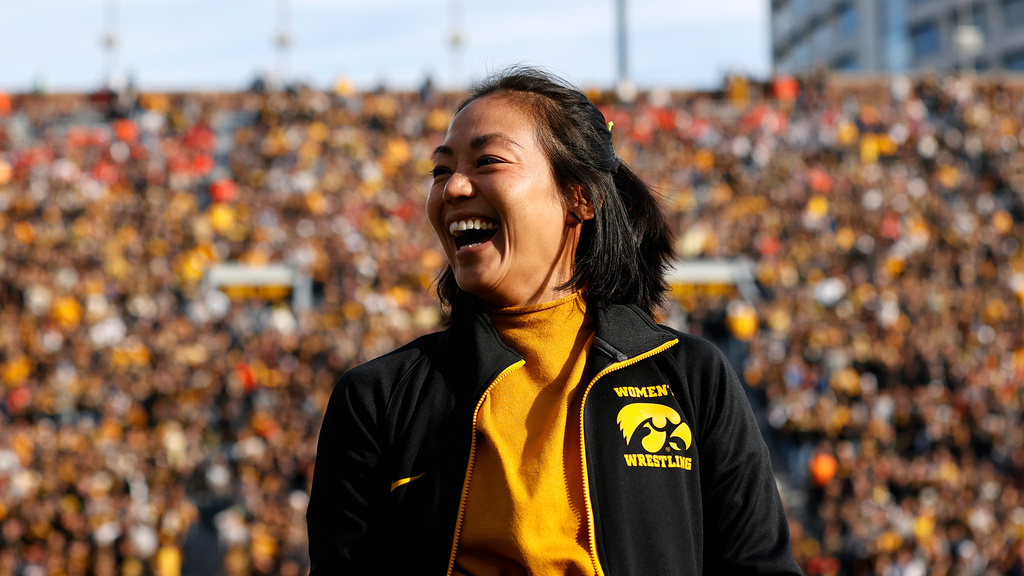 A woman smiling in front of a crowded stadium