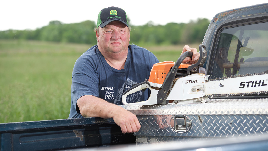 a man holding a chain saw by his truck