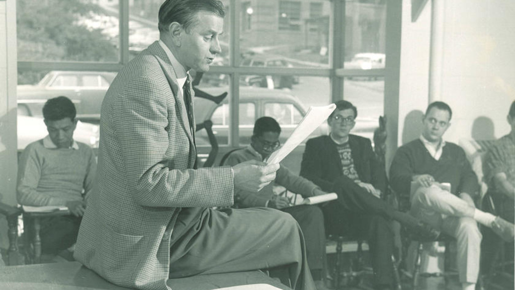A man sitting on a desk reading