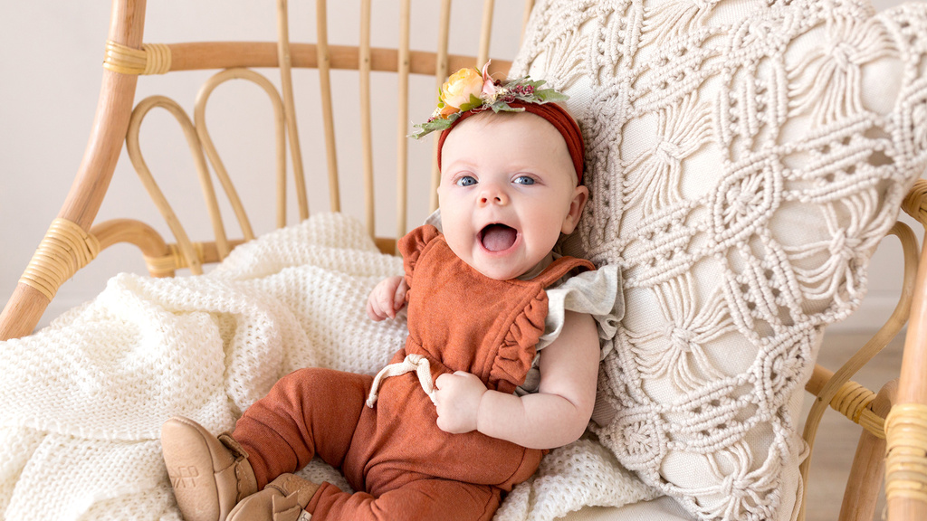 A baby sitting in a chair smiling