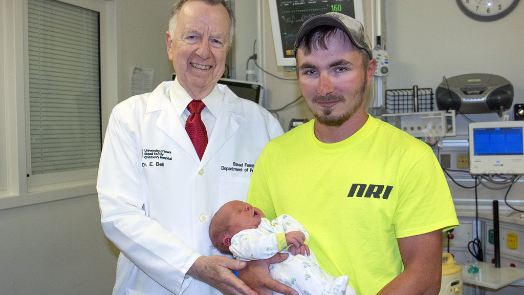 A doctor standing with a man holding his baby