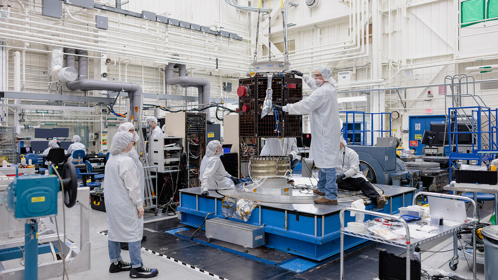 One of the TRACERS spacecraft is fitted with lift support equipment inside a clean room at Millennium Space Systems Small Satellite Factory