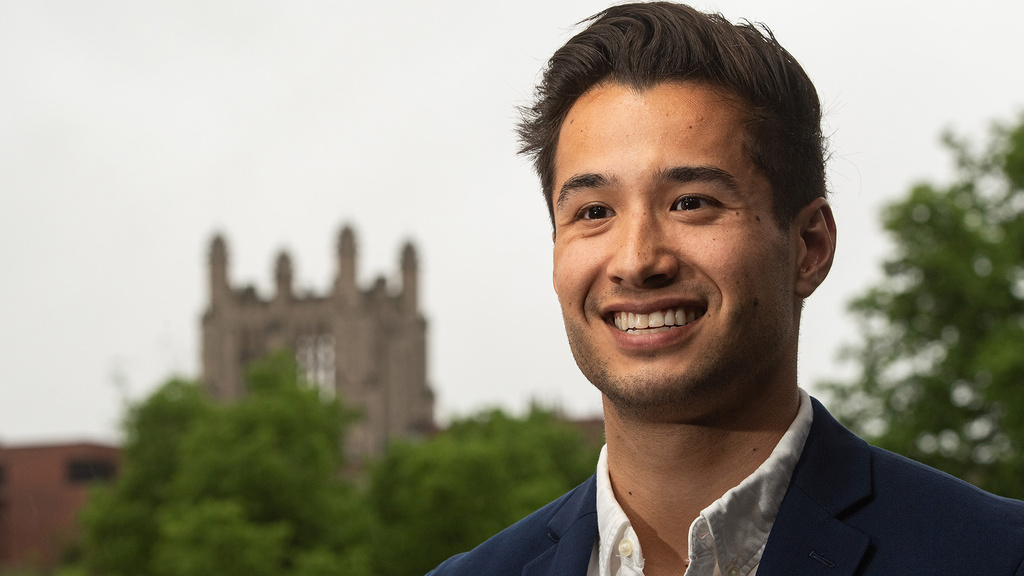 a man standing on the university of iowa campus with a gothic structure visible in the background