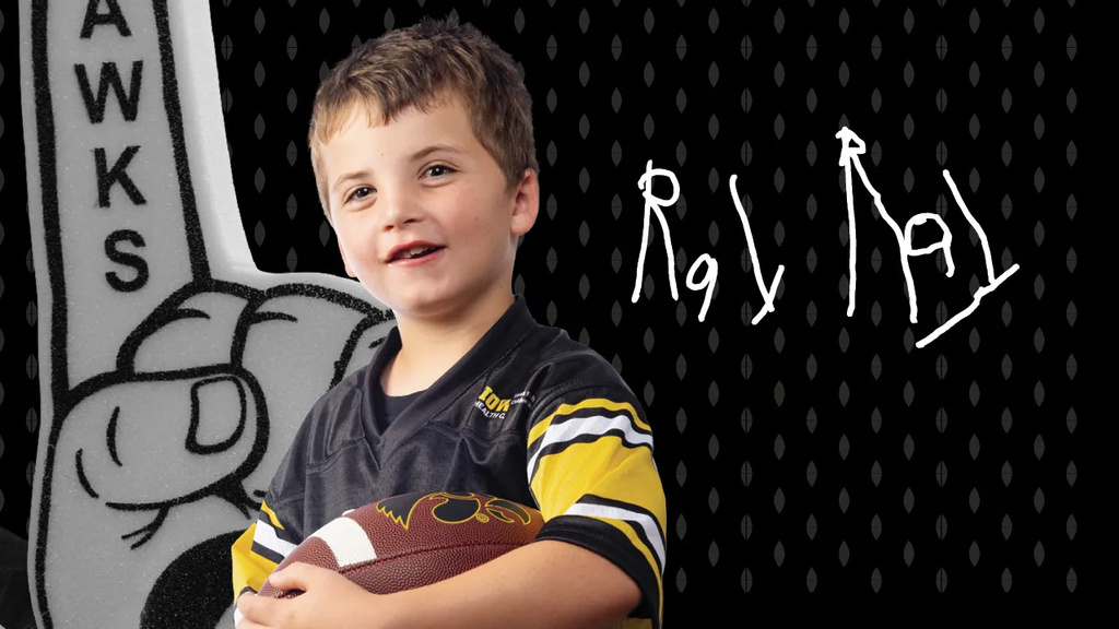 Kid Captain Ray Walker holding a football; the photo backdrop features a foam finger and Ray's signature