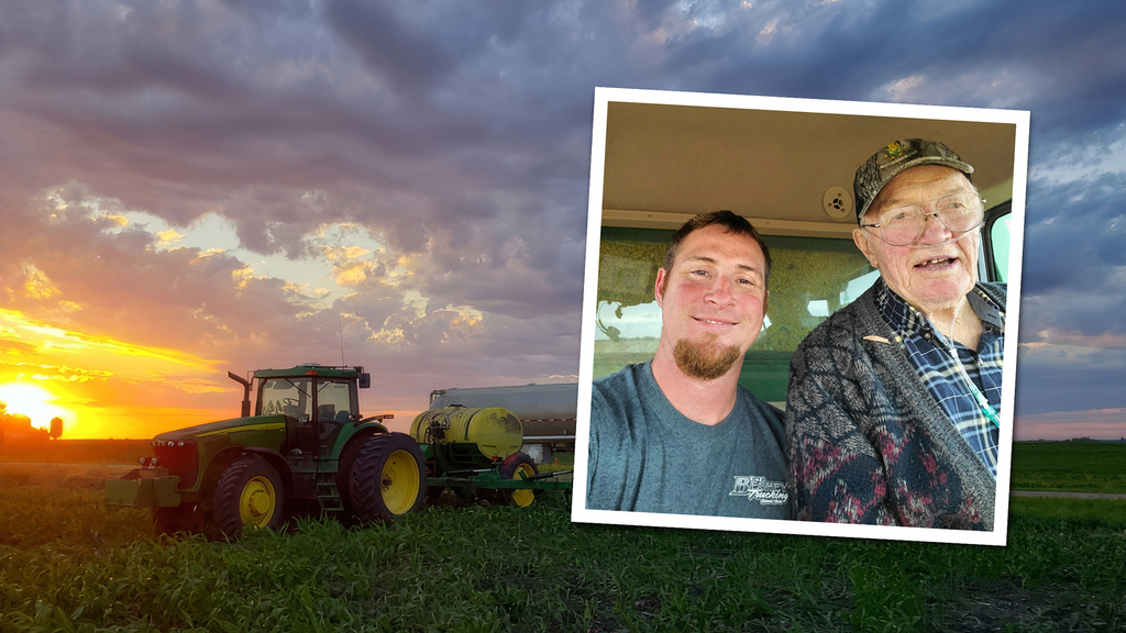a selfie of two men is set within a shot of a tractor in a field, with the sun low in the sky