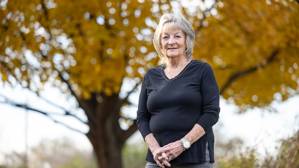 a woman posing outdoors near a tree with golden leaves