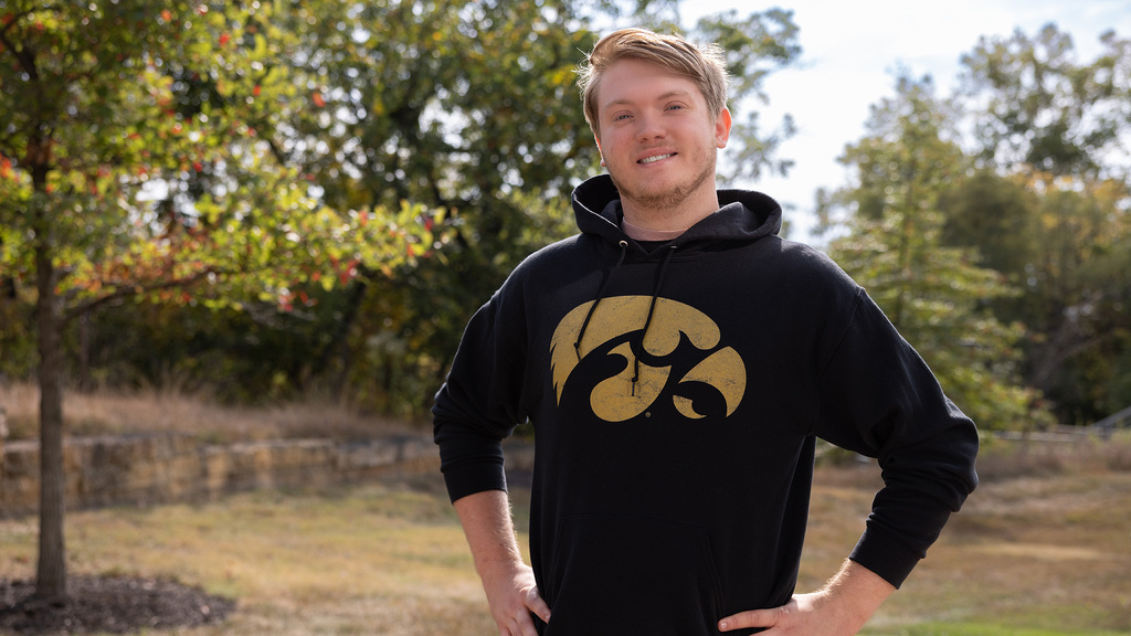 a young man wearing a sweatshirt with the tiger hawk logo stands outdoors
