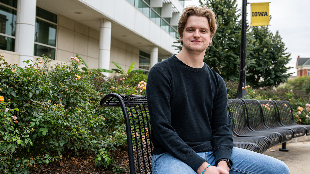 University of Iowa student Tyler Draayer sits on a bench on campus