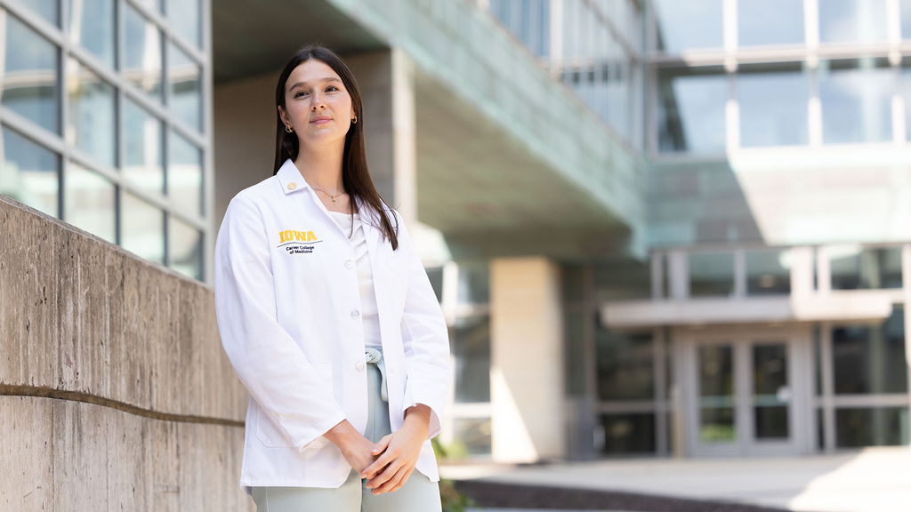 a woman wearing a white coat stands outside a medical building