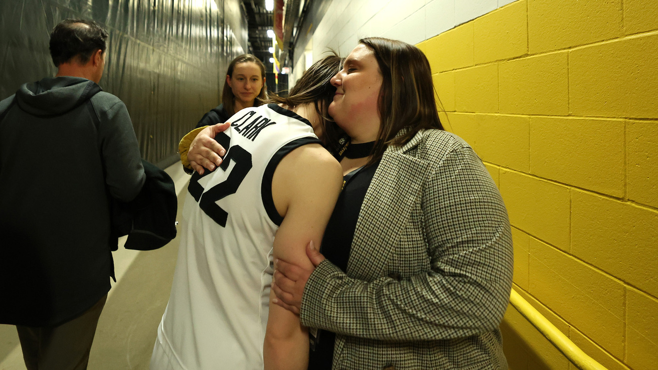 A woman smiling while hugging a basketball player