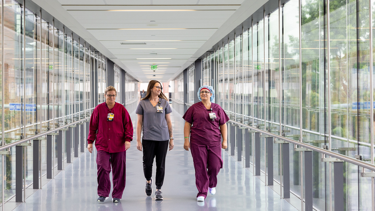 Three nurses walking down a skywalk