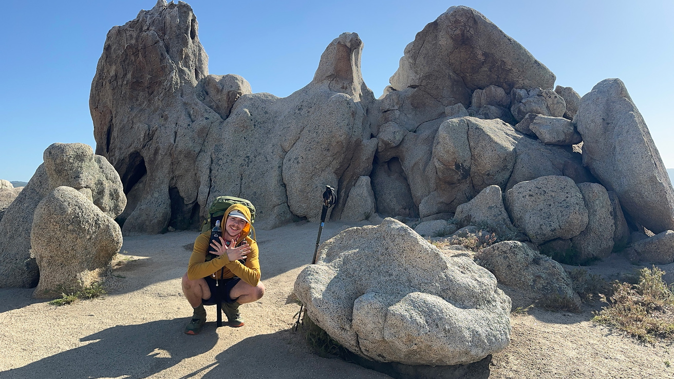 a man crouching near some boulders