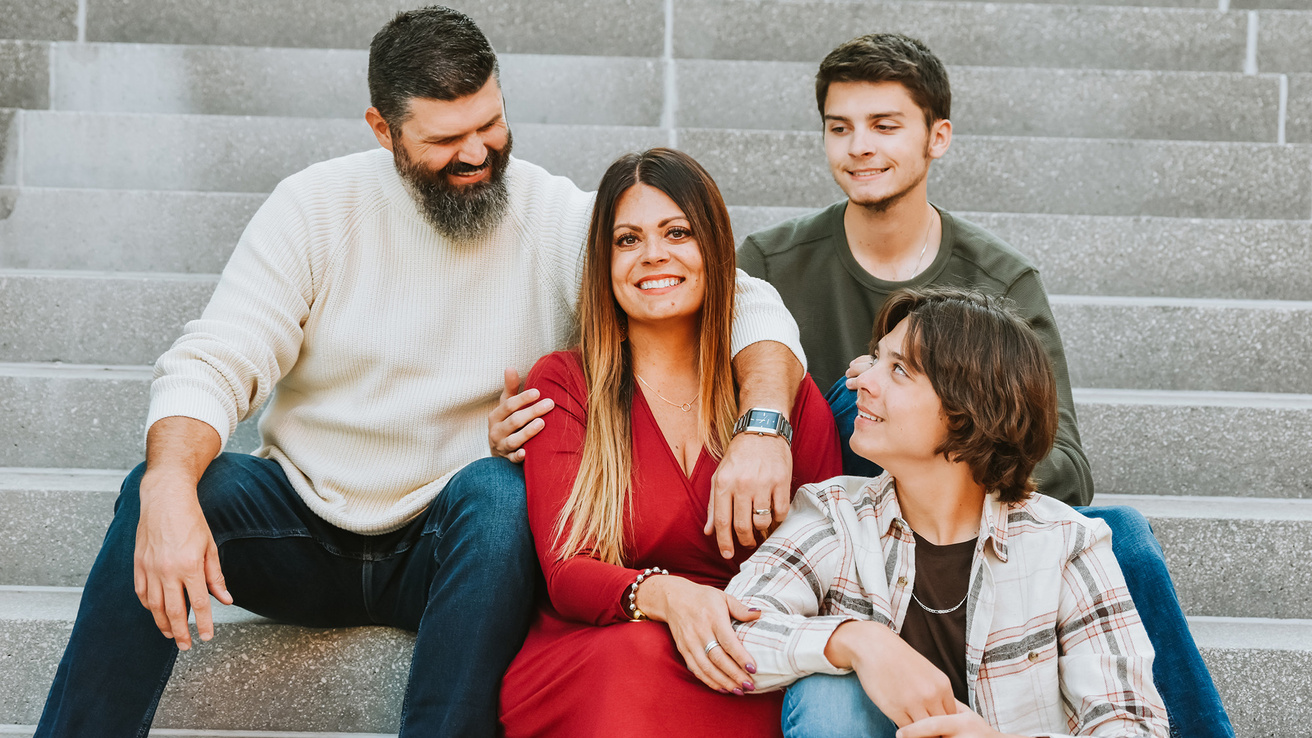 A family sitting on steps looking at the matriarch while smiling