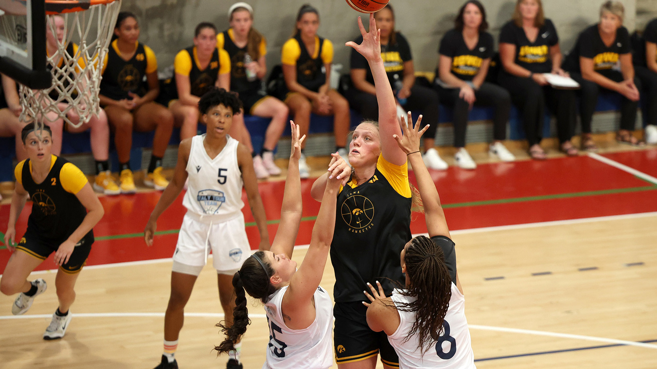 A basketball player going up for a shot jumping over two defenders