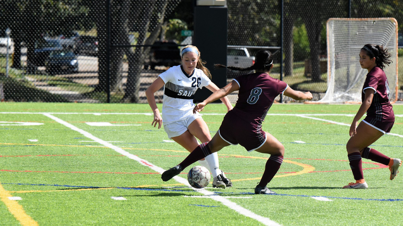 A soccer player dribbling the ball past her opponents
