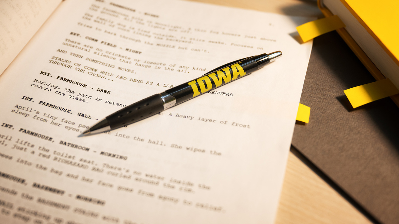 a pen with the Iowa logo rests on a screenplay