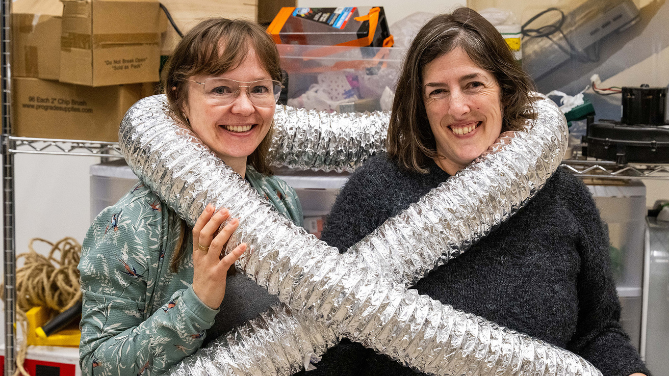 two professors with tubing wrapped around them