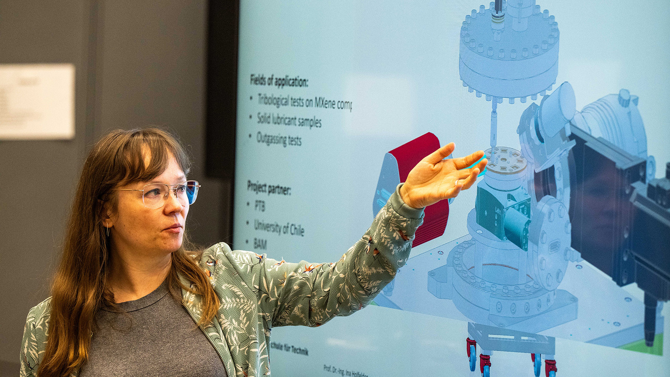 a woman gestures toward a screen displaying a presentation