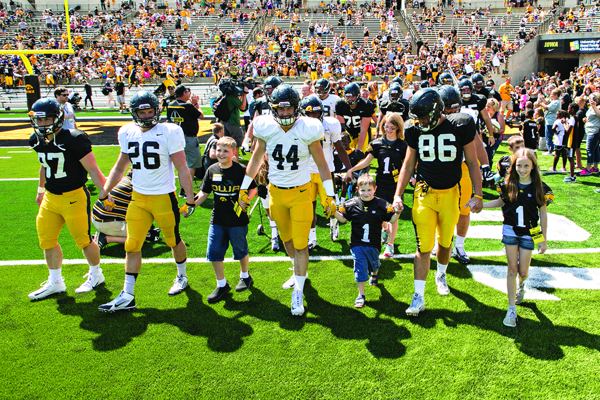 university of iowa football players and kid captains take the field in swarm formation