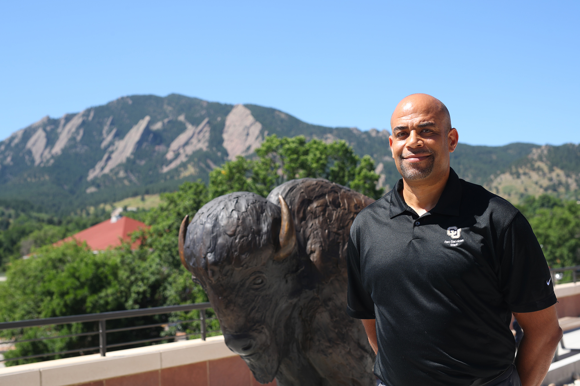 university of iowa alumnus tony price standing on the university of colorado boulder campus with the mountains in the background