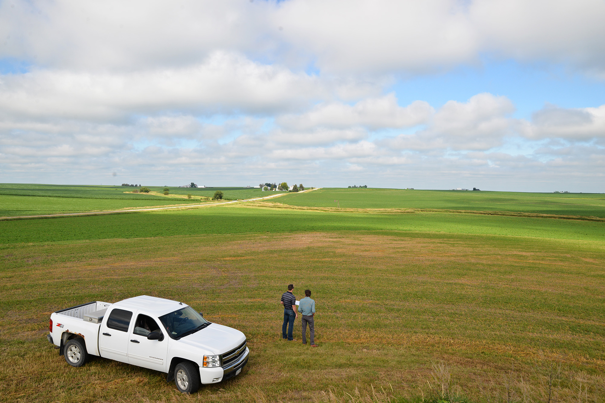 two men stand in a field and discuss the watershed and landscape above the community of Vinton