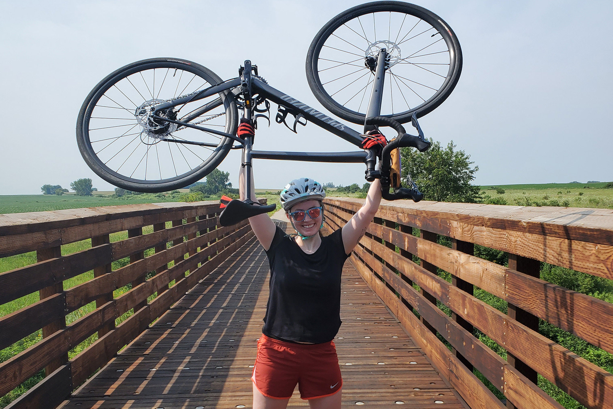Kami Waalkens holding her bicycle over her head