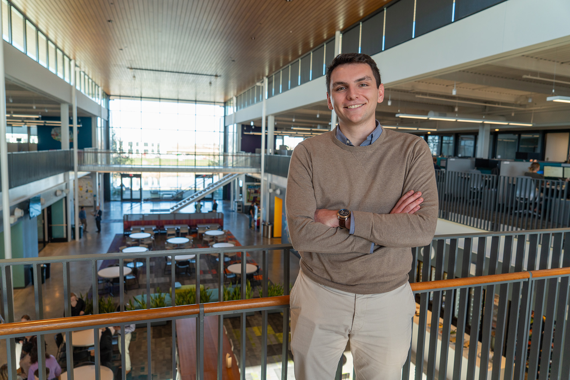 University of Iowa graduate Will Corbin standing on a second-level walkway in a building with an open floor concept