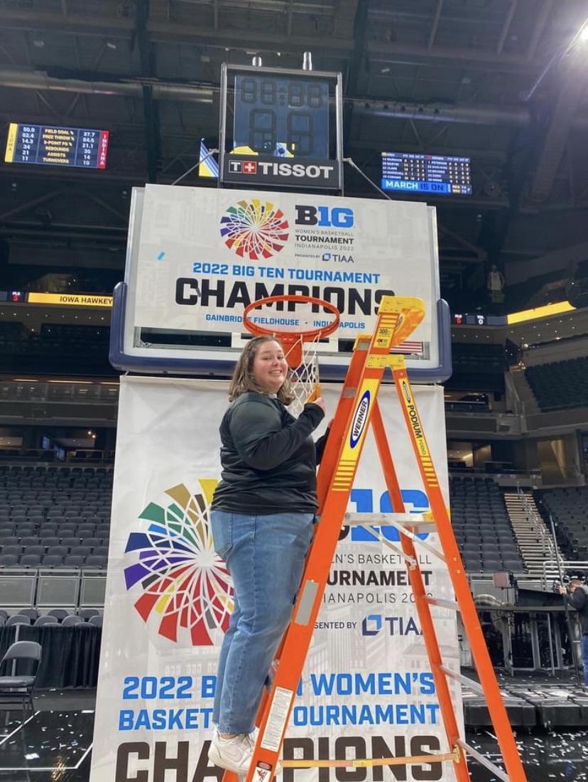 Hawkeye Marching Band member Olivia Goodyear cuts down part of the net after the Iowa women's basketball team won the Big Ten Tournament Championship.